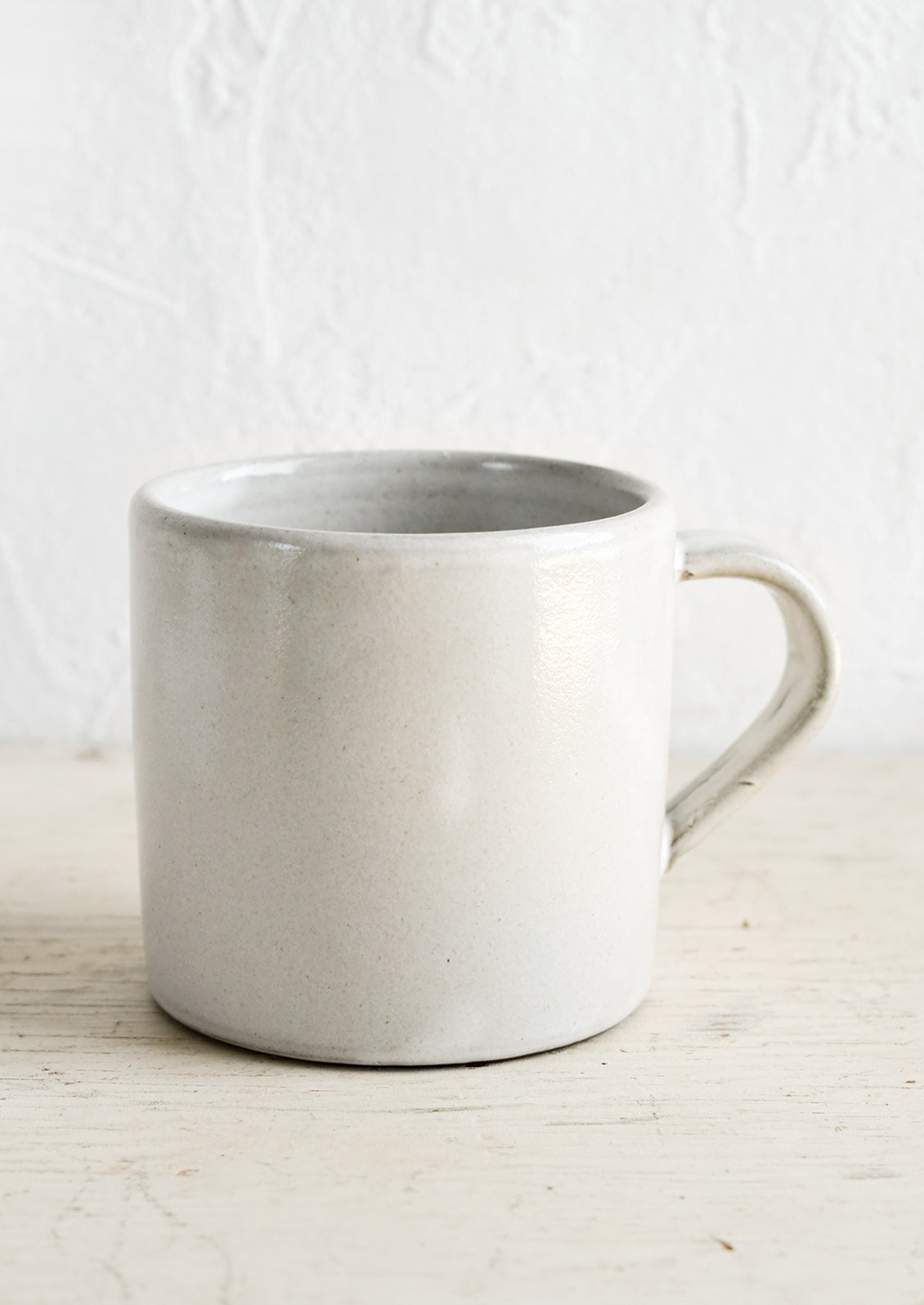 A ceramic coffee mug in a simple, classic shape in a white glaze over brown clay.