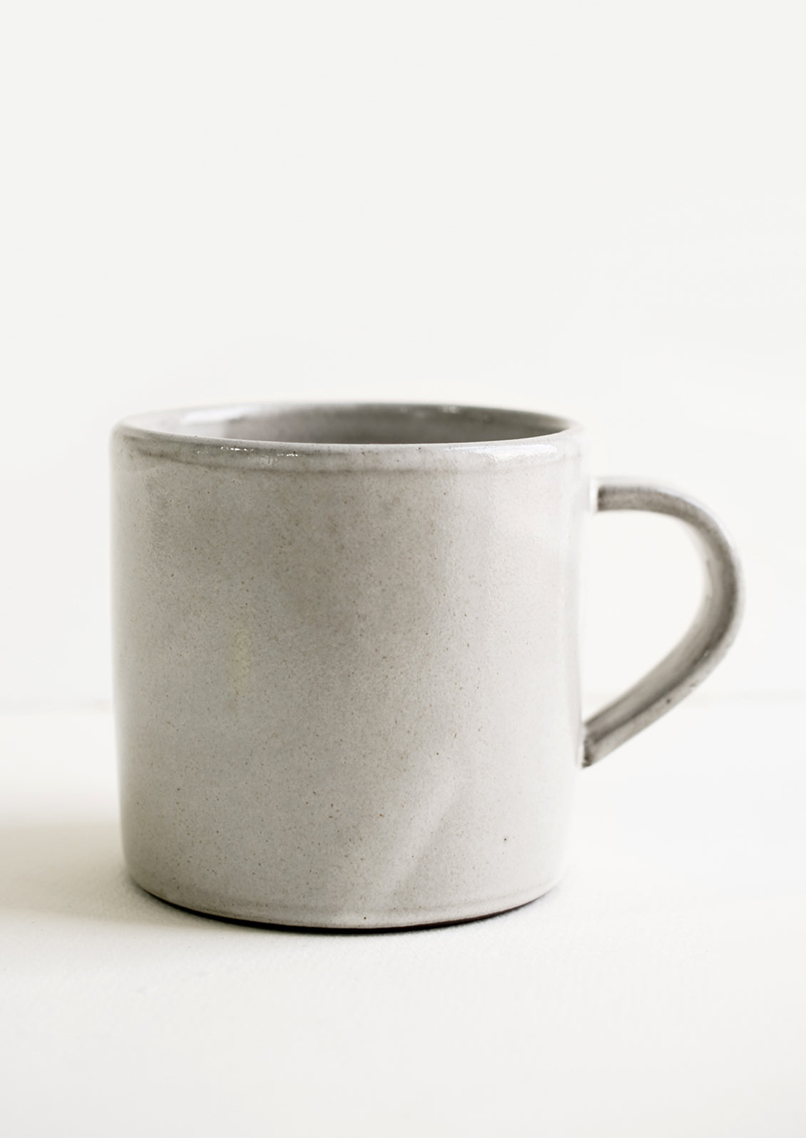 A ceramic coffee mug in a simple, classic shape in a white glaze over brown clay.