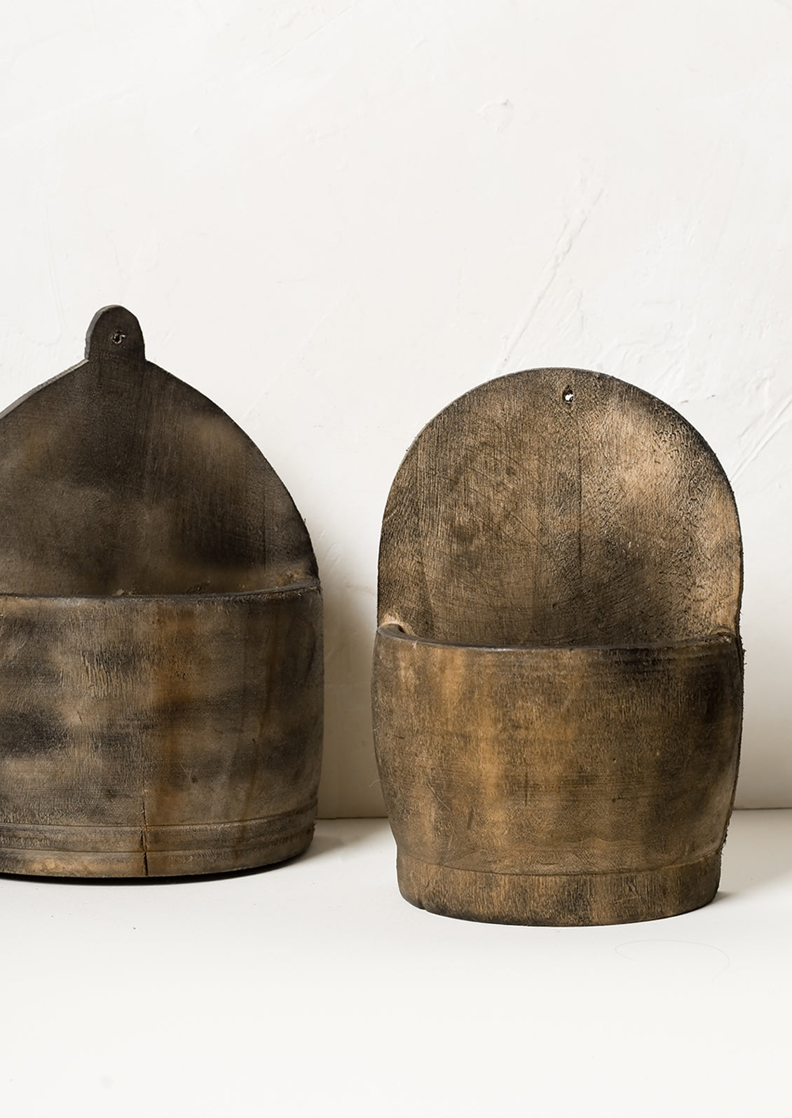 Two vintage looking wooden wall baskets in slightly different shapes.