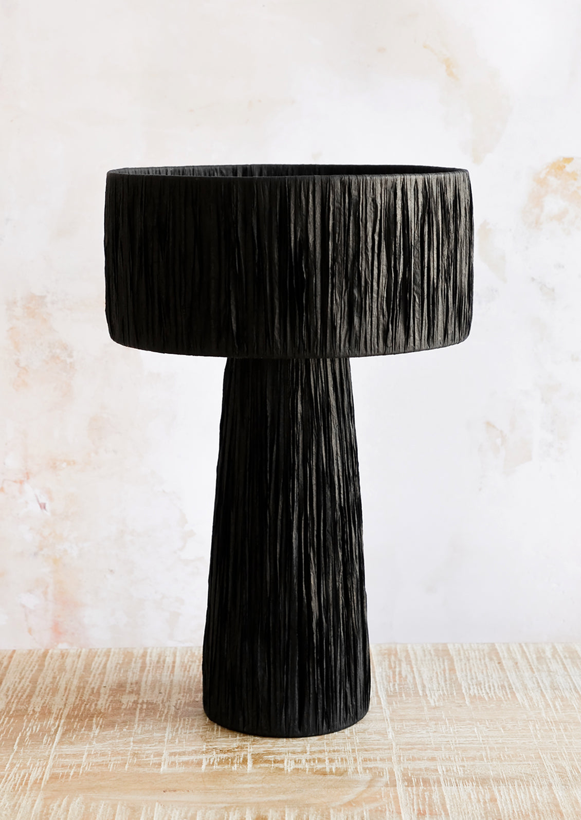 A table lamp wrapped in black raffia.