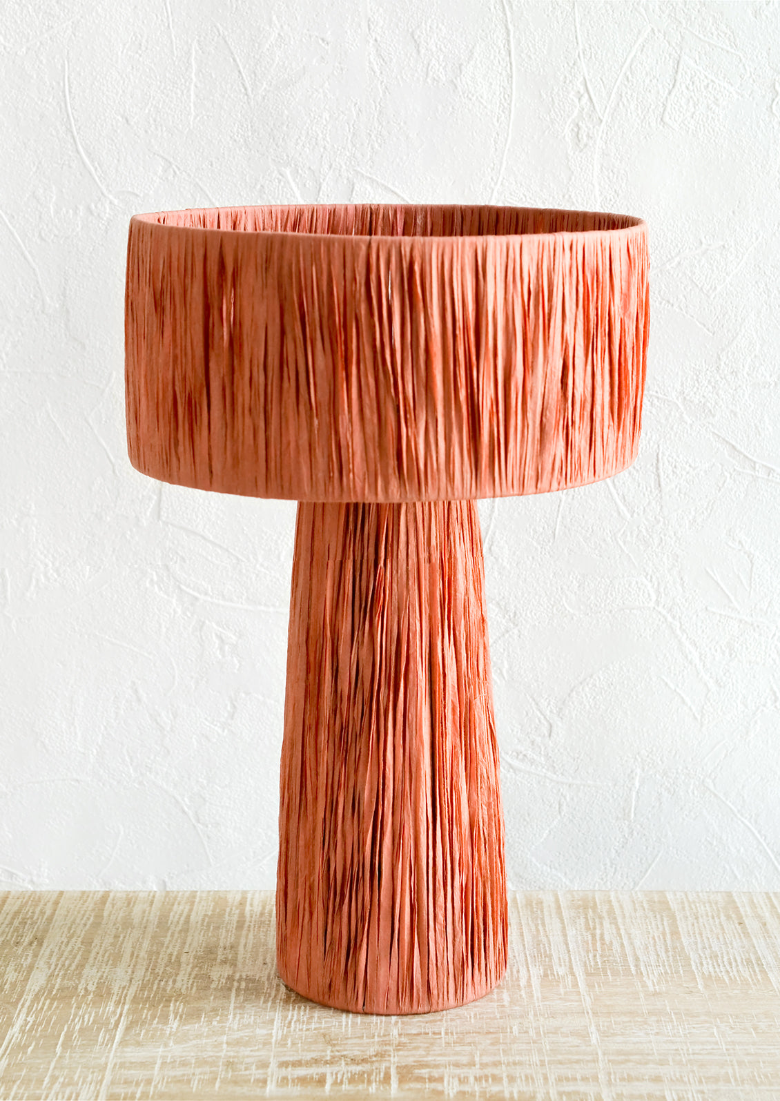 A table lamp wrapped in peach raffia.