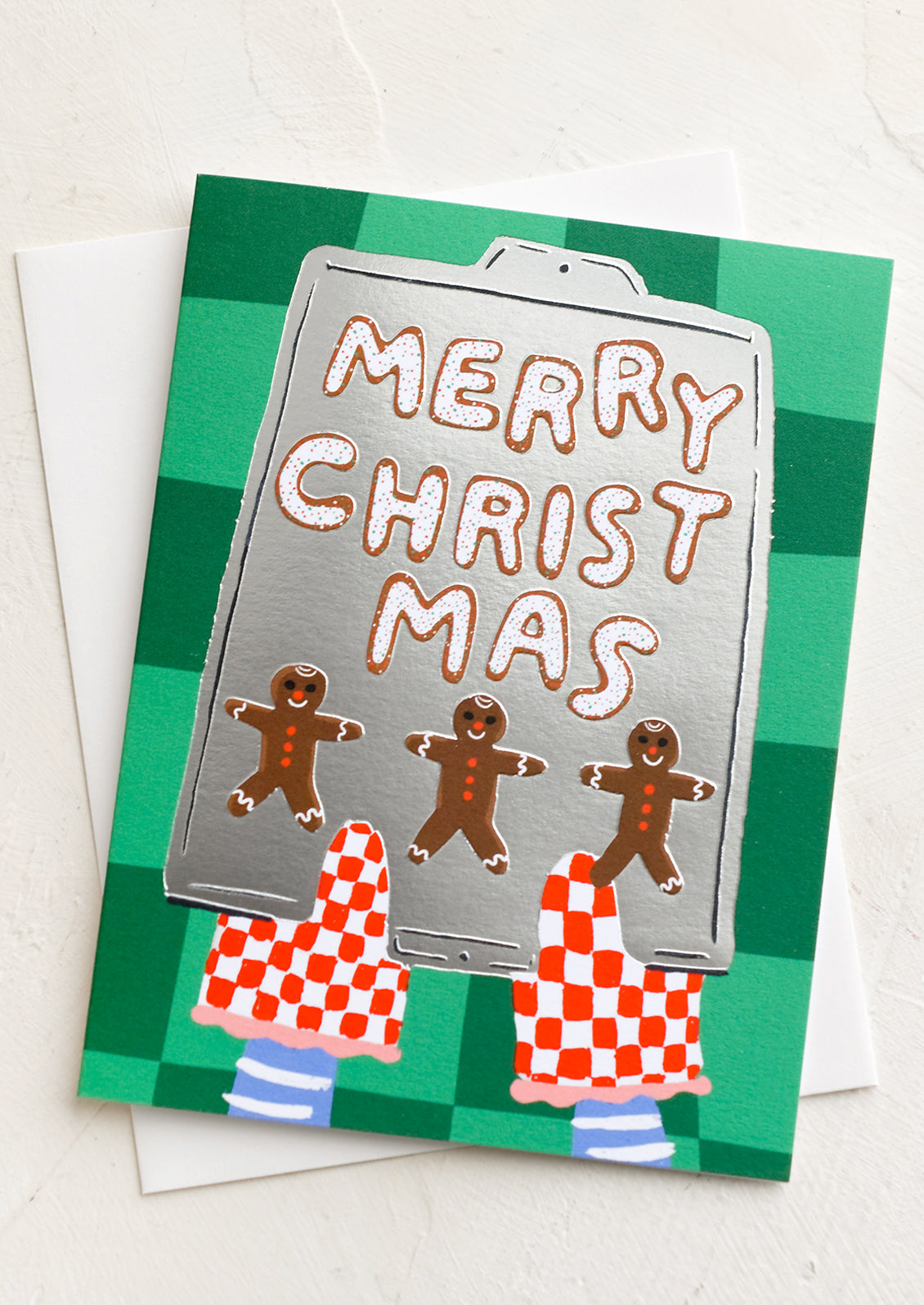 A card with illustration of gingerbread men cookies on a tray, text reads "Merry Christmas".