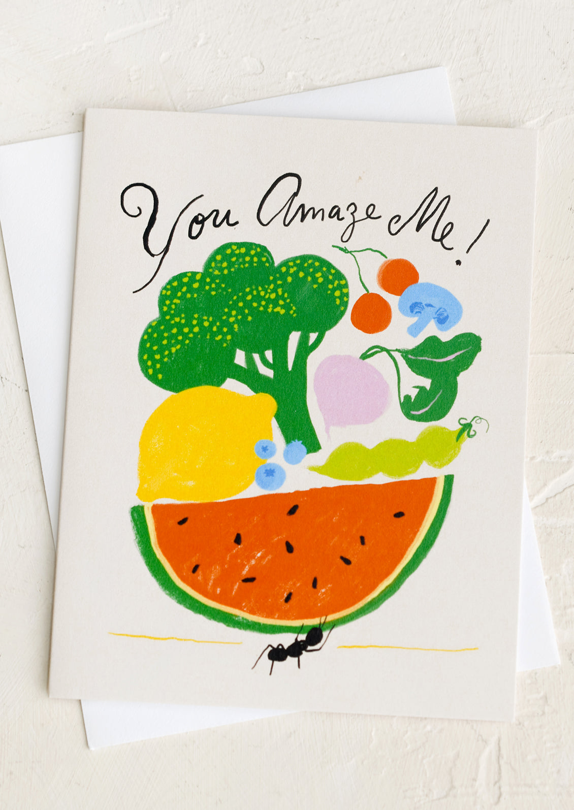 A greeting card with illustration of an ant holding up lots of fruit, text reads "You amaze me!".