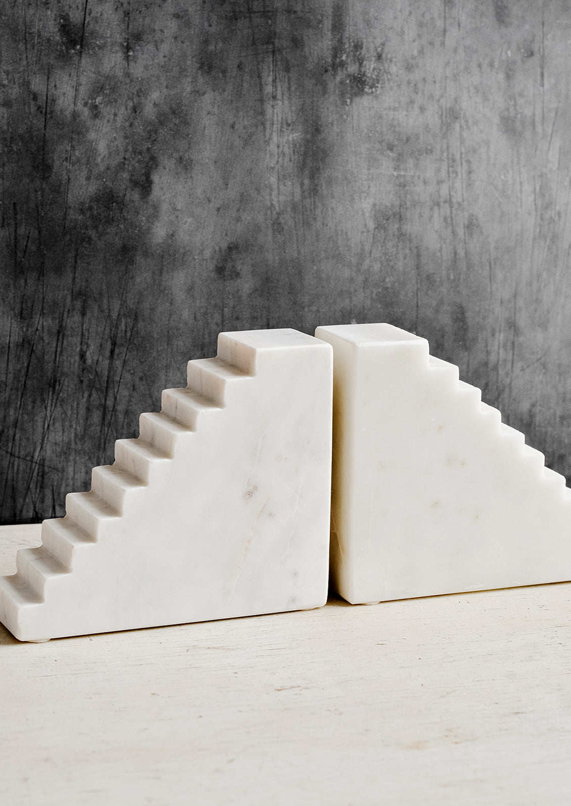 A pair of white marble bookends with staircase design.