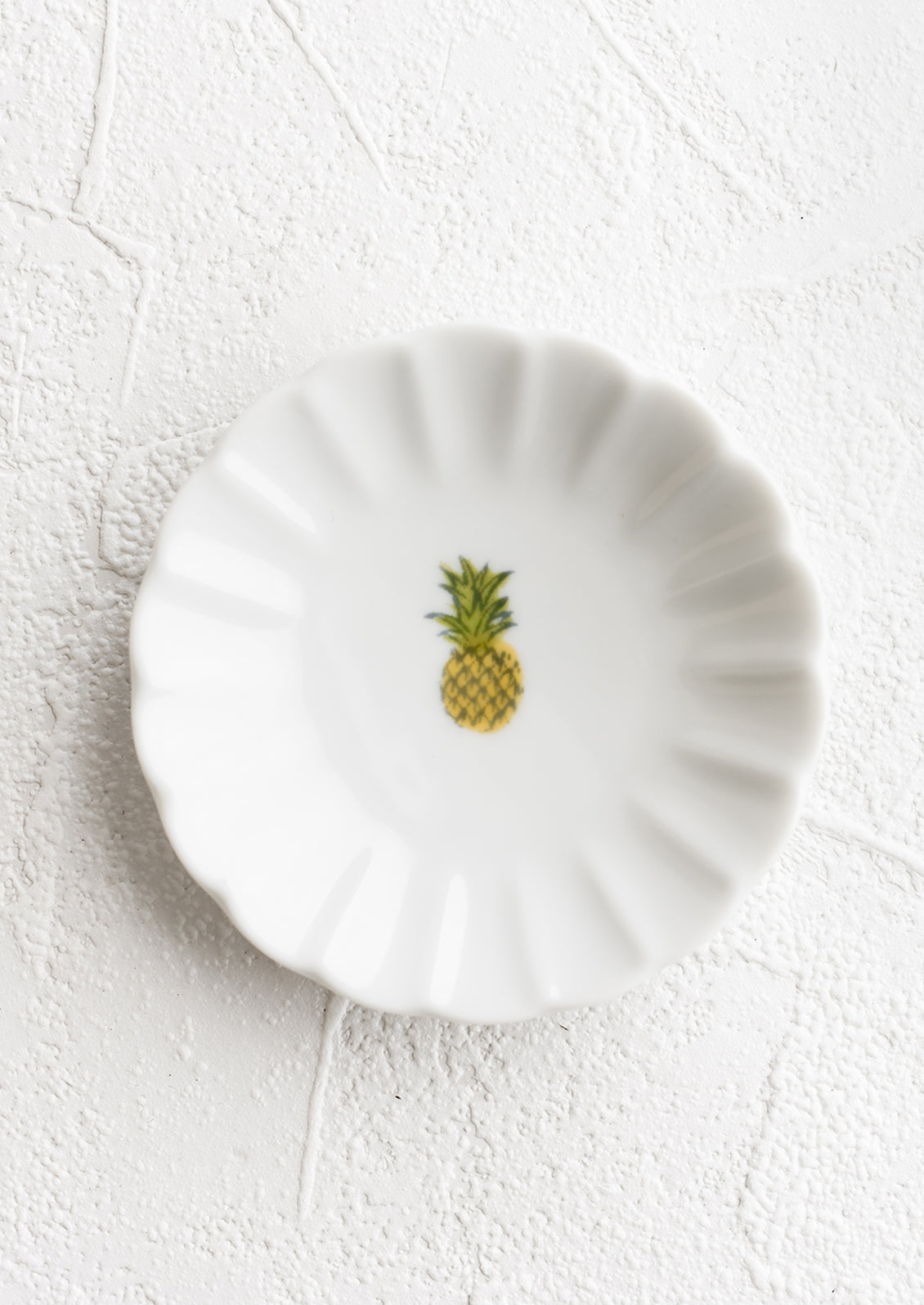 A round dish with scalloped trim and pineapple icon.