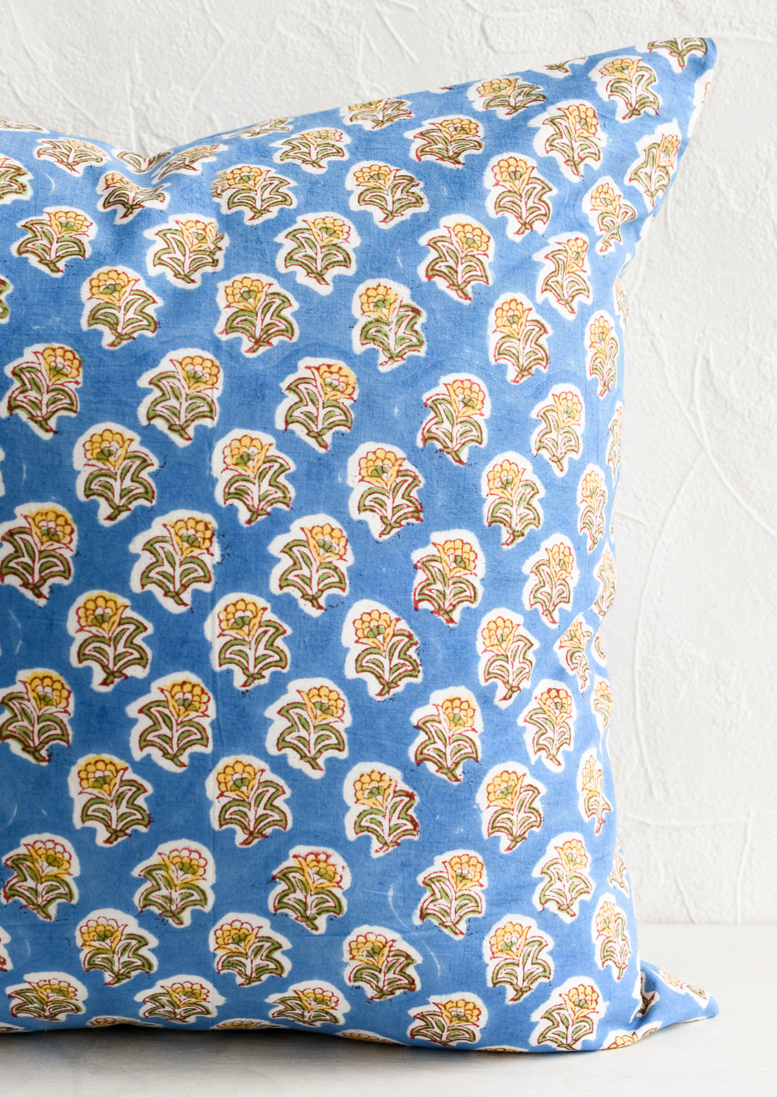 A block printed throw pillow in blue and yellow floral.